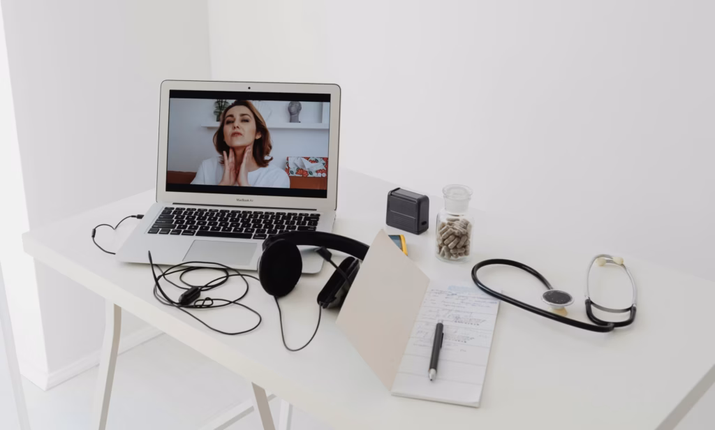 Telehealth consultation on a laptop with medical tools and notes on a white desk, representing digital healthcare and the importance of centralized documentation for FDA 510(k) medical device submissions.